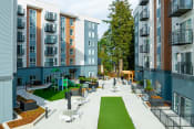Thumbnail 2 of 22 - Apartments for Rent in Shoreline, WA - Quinn by Vintage - Courtyard with Seating Area, Playground, and View of Apartments Complex