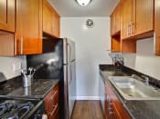 Thumbnail 9 of 26 - The Post Apartments kitchen with dark wood cabinets and stainless steel appliances