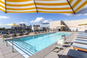 Thumbnail 12 of 27 - Pool sun deck with teak lounge chairs and yellow striped umbrellas and Stamford skyline in background