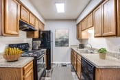 Thumbnail 1 of 32 - Apartments for Rent in Fort Worth- Monarch Pass- Kitchen with Black Appliances, Wooden Cabinets, and Tile Backsplash