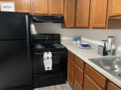Thumbnail 7 of 12 - a kitchen with black appliances and wooden cabinets and a sink