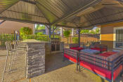 Thumbnail 31 of 35 - Pet-Friendly Apartments in Beaverton, OR - MonteVista - Outdoor Grill Area with Eat-in Bar, Barstools, Comfortable Seating, and Greenery