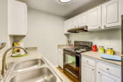 Thumbnail 20 of 35 - Beaverton Apartments for Rent - MonteVista - Galley Kitchen with White Cabinetry, Granite Countertops, and Fully Loaded Appliances
