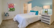 Thumbnail 10 of 24 - Rutland Place Apartments in Macon Georgia photo of a bedroom with a large white bed with blue pillows and a pink flower on the wall