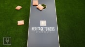 Thumbnail 4 of 40 - a tennis court with chairs on the grass and the heritage towers apartments logo
