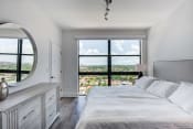 Thumbnail 2 of 19 - Dog-Friendly Apartments In Miami, FL - MB Station - Spacious Bedroom With Wood-Style Flooring, Modern Light Fixtures, And A Large Window Overlooking The Neighborhood