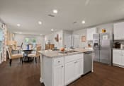 Thumbnail 4 of 20 - a white kitchen with a large island and a stainless steel refrigerator