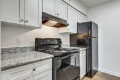 Thumbnail 2 of 19 - Whitney Manor Apartments in Gretna, LA photo of kitchen with black appliances and grey cabinets