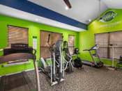 Thumbnail 18 of 30 - the gym is equipped with cardio equipment and green walls