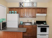 Thumbnail 4 of 31 - apartment kitchen with wood cabinets and white appliances