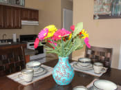 Thumbnail 5 of 31 - a vase of flowers on a table with plates and cups