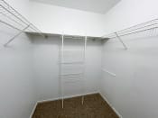 Thumbnail 8 of 21 - a spacious walk in closet in a bedroom with white walls