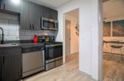 Thumbnail 8 of 25 - Nashville Apartments - The Canvas - Modern Kitchen with Soft-Close Wood-Inspired Cabinets, Stainless-Steel Appliances, and Hardwood-Inspired Flooring and Stainless Steel Appliances
