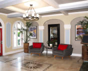 Thumbnail 24 of 28 - Pasadena Brookmore apartments lobby seating area with large gray midcentury chairs with red pillows on a marble tile floor.