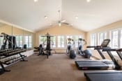Thumbnail 16 of 23 - a home gym with exercise machines and a ceiling fan