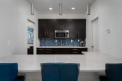 Thumbnail 14 of 25 - a kitchen with a large island with a white counter top and blue chairs