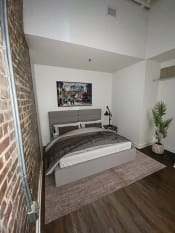 Thumbnail 7 of 13 - a bedroom with a bed and a brick wall