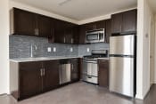 Thumbnail 7 of 13 - a kitchen with wooden cabinets and stainless steel appliances