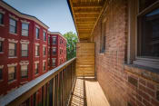 Thumbnail 6 of 25 - a balcony with a wooden railing and a brick building in the background