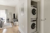 Thumbnail 17 of 22 - a living room with a washer and dryer and a tv on a stand