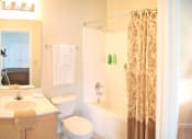 Thumbnail 10 of 36 - a bathroom with a sink toilet and tub and a shower curtain at Chester Village Green Apartments, Chester, Virginia