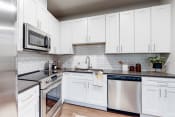 Thumbnail 27 of 62 - a white kitchen with stainless steel appliances and white cabinets