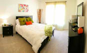 Thumbnail 14 of 36 - a bedroom with a white bed and green and orange pillows at Chester Village Green Apartments, Chester, Virginia