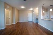 Thumbnail 29 of 30 - an empty living room with wood flooring and a kitchen