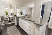 Thumbnail 4 of 40 - an open kitchen with granite counter tops and a dining room with a table at Ansley at Town Center in Evans GA