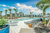 Thumbnail 7 of 18 - a swimming pool with lounge chairs and palm trees at Livano Nature Coast, Spring Hill, FL 34608