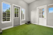 Thumbnail 14 of 20 - a living room with green astroturf and a door with three windows