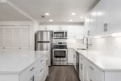 Thumbnail 6 of 34 - Kitchen with stainless steel appliances, white cabinetry, and quartz countertop