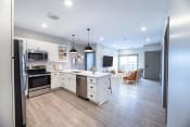 Thumbnail 18 of 52 - a kitchen and living room with white cabinets and stainless steel appliances at The Commons at Rivertown, Grandville, Michigan, 49418