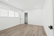 Thumbnail 21 of 23 - an empty living room with white walls and wood flooring