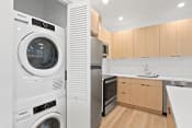 Thumbnail 33 of 57 - a white washer and dryer in a kitchen with wooden cabinets