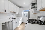 Thumbnail 2 of 23 - a white kitchen with white cabinets and stainless steel appliances