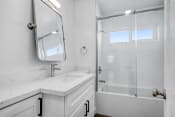 Thumbnail 10 of 23 - a white bathroom with a shower and a sink and a mirror