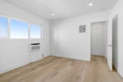 Thumbnail 8 of 23 - a living room with white walls and wooden floors and a window