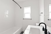 Thumbnail 21 of 43 - a white bathroom with a tub and a sink and a window