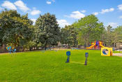 Thumbnail 16 of 26 - a grassy area with a playground in the background