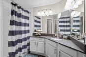 Thumbnail 47 of 52 - a bathroom with gray cabinets and a blue and white striped shower curtain