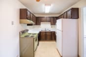 Thumbnail 11 of 16 - A kitchen with white appliances and brown cabinets and a refrigerator. Bismarck, ND Eastbrook Apartments .