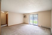 Thumbnail 8 of 16 - Bismarck, ND Eastbrook Apartments. A spacious living room with a sliding glass door leading to a yard