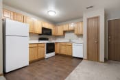 Thumbnail 4 of 10 - Omaha, NE Deerfield Apartments. A kitchen with white appliances and wooden cabinets