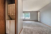 Thumbnail 9 of 24 - Omaha, NE Woodland Pines Apartments. A living room with a laundry closet with a washer and dryer in it.