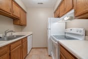Thumbnail 19 of 24 - Omaha, NE Woodland Pines Apartments. A kitchen with wooden cabinets and white appliances