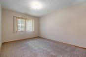 Thumbnail 21 of 24 - Omaha, NE Woodland Pines Apartments. A bedroom with a window and a carpeted floor