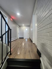Thumbnail 77 of 79 - a long hallway with wood floors and white brick walls and a staircase