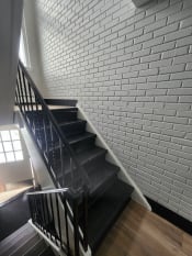 Thumbnail 78 of 79 - a staircase with black stairs and a white brick wall