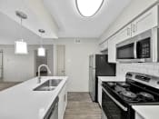 Thumbnail 28 of 37 - a kitchen with white countertops and stainless steel appliances